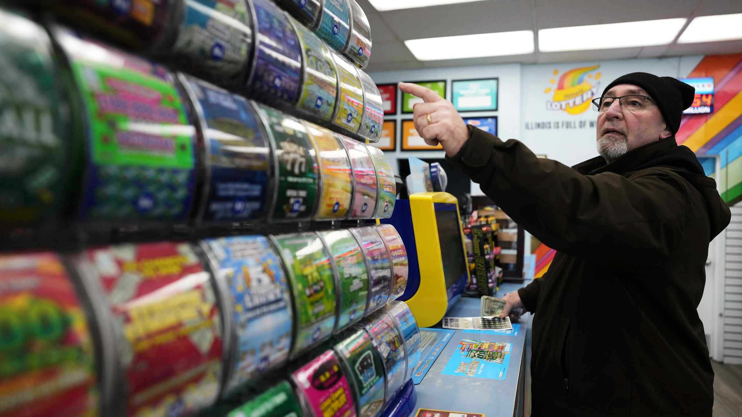 A man points to a selection of scratch-off lottery cards.